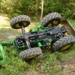 Green tractor upside down in a ditch