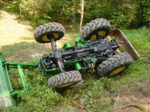 Green tractor upside down in a ditch
