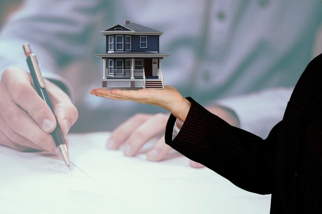 person signing a contract overlay of a house in hand of realtor 