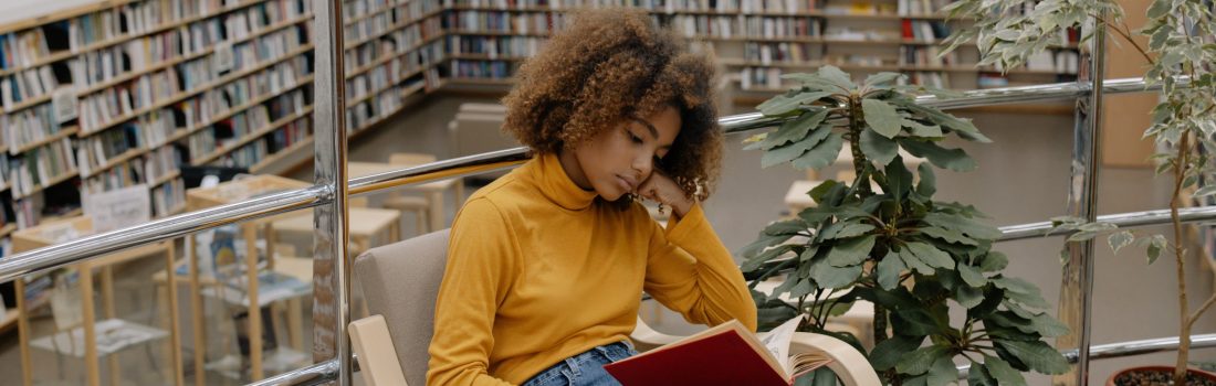 Girl sitting in a library reading a book